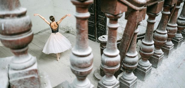 A person balancing on one leg in a wide, spacious hall.
